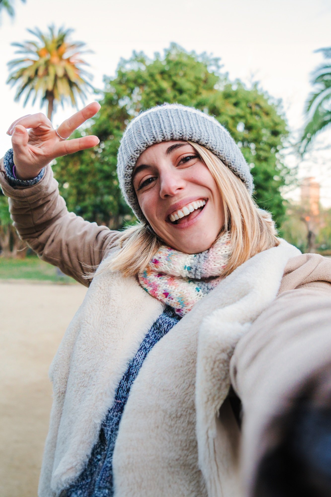 Vertical individual portrait of one happy caucasian blonde girl smiling taking a selfie portrait
